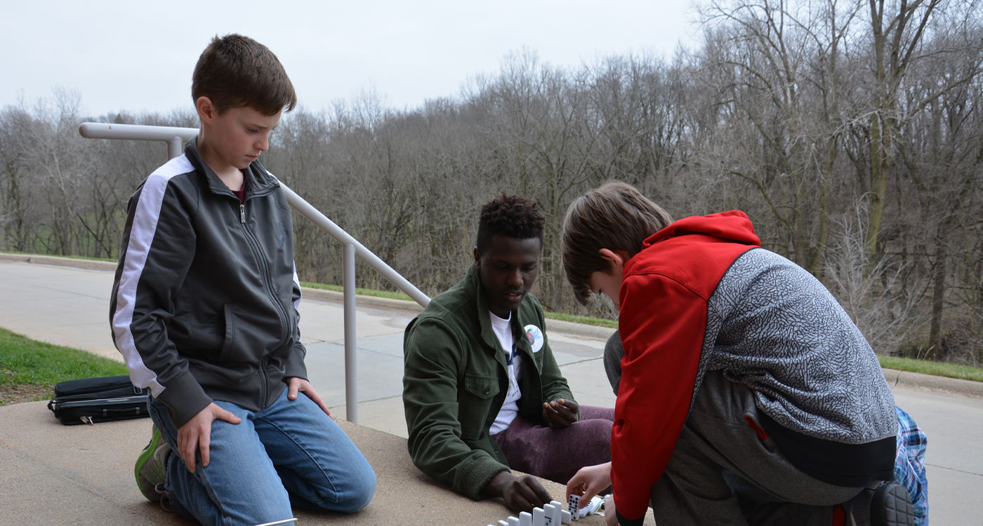WPU student with secondary education students set up dominoes for a chain reaction